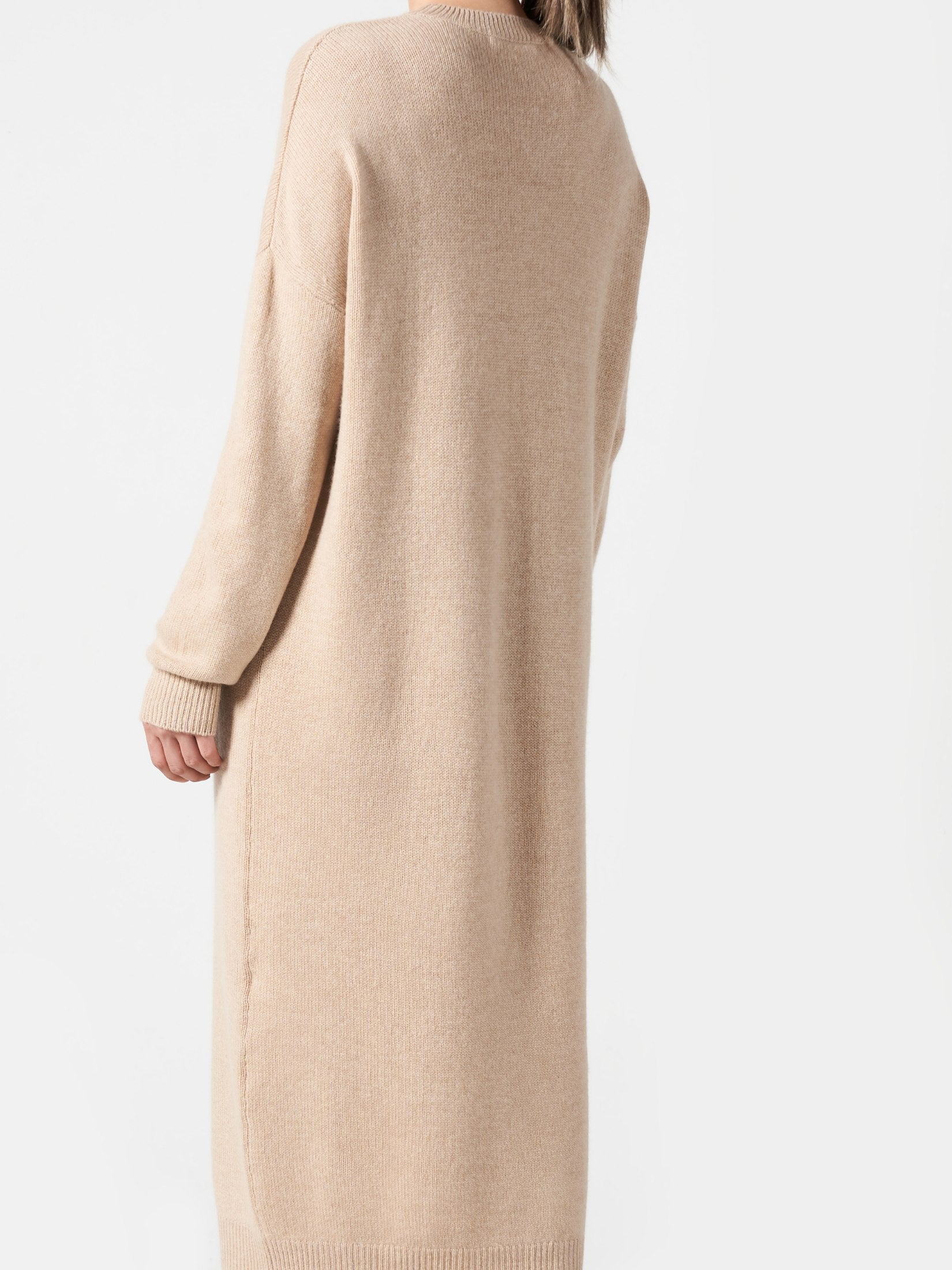Back view of a camel color cashmere loose dress with long sleeves and a relaxed fit on a woman.