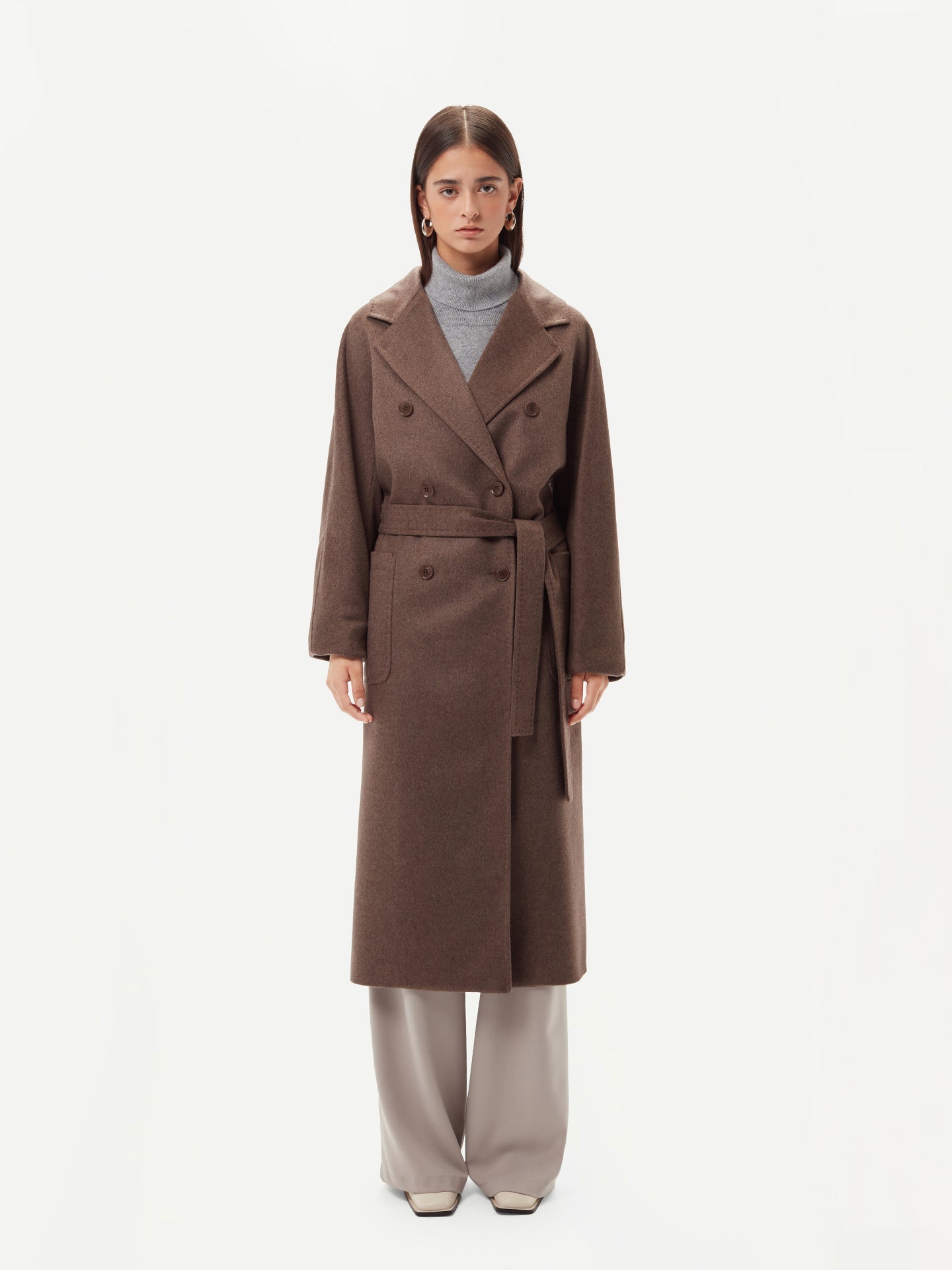 A model wearing a warm brown cashmere coat, styled with a belted waist for an elegant and cozy look.