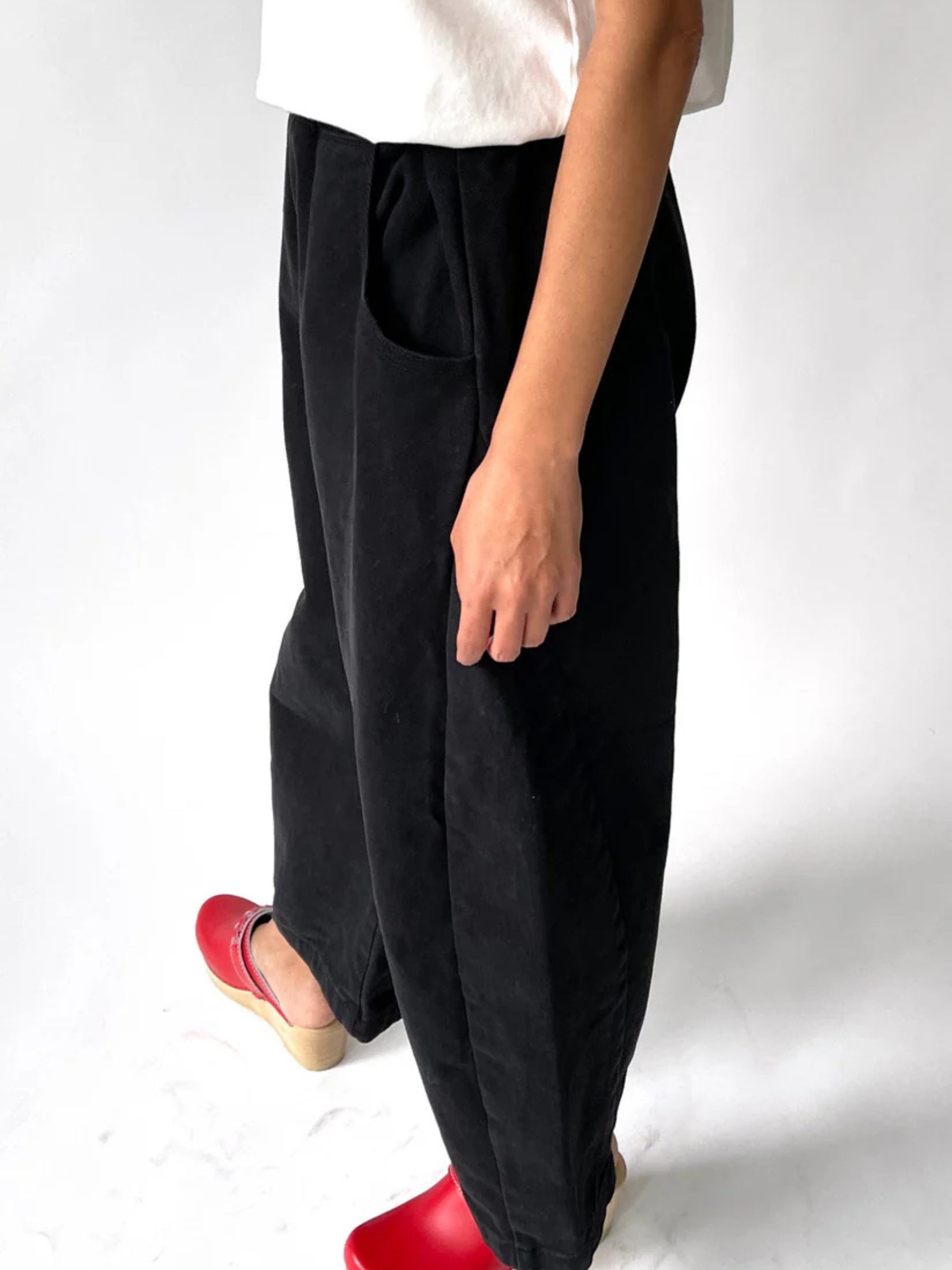 Model wearing black canvas arc pants with a relaxed, modern fit