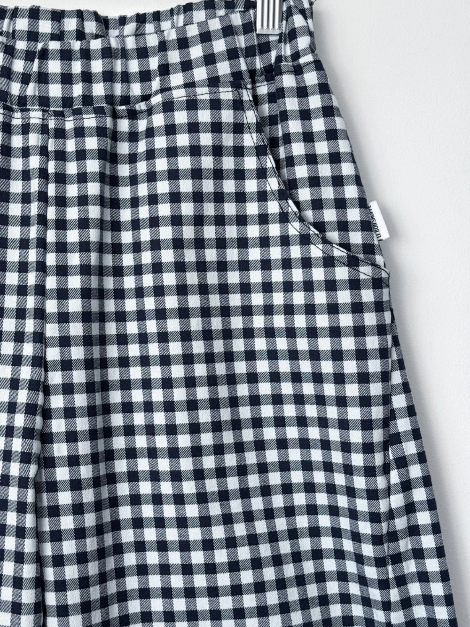 Pocket detail of navy gingham arc pants, showcasing their structured design.