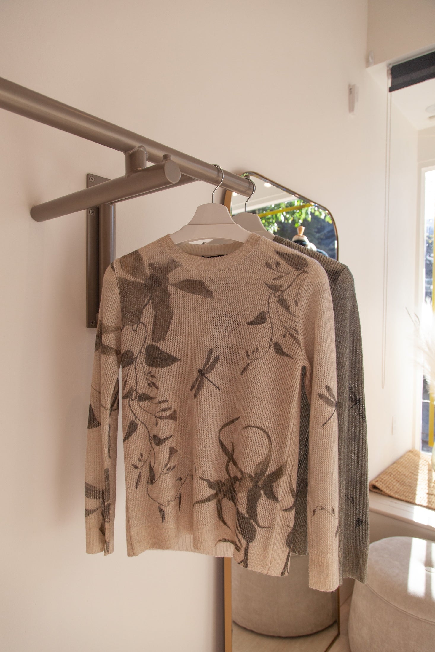 Beige cashmere crewneck sweater with dragonfly print, on hanger, showcasing a delicate design and soft, luxurious texture.