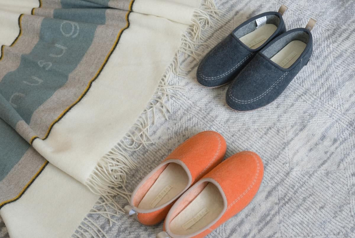 grey and orange felt slippers, highlighting their soft material and comfortable, casual design.