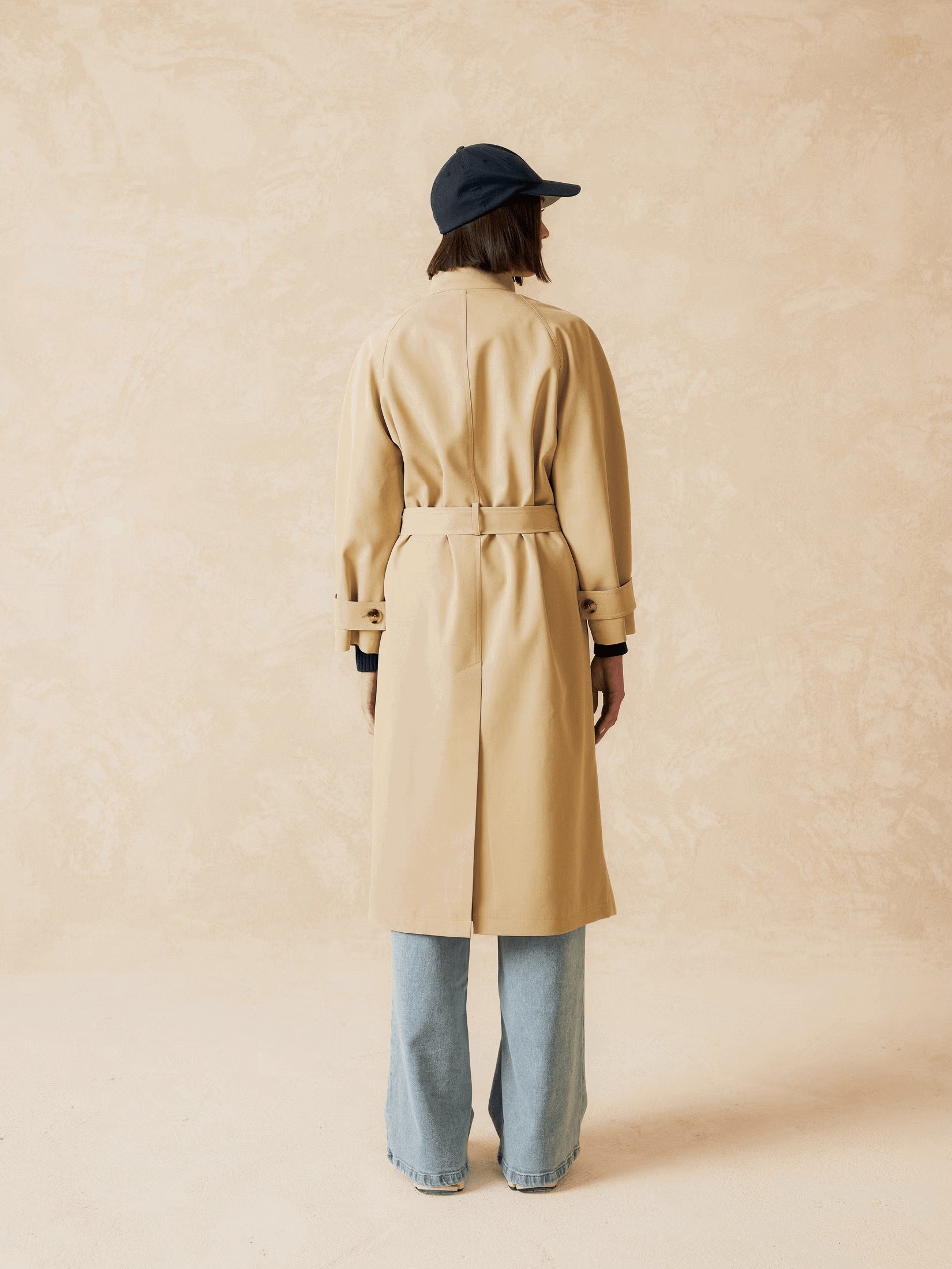 Back view of a long beige trench coat.