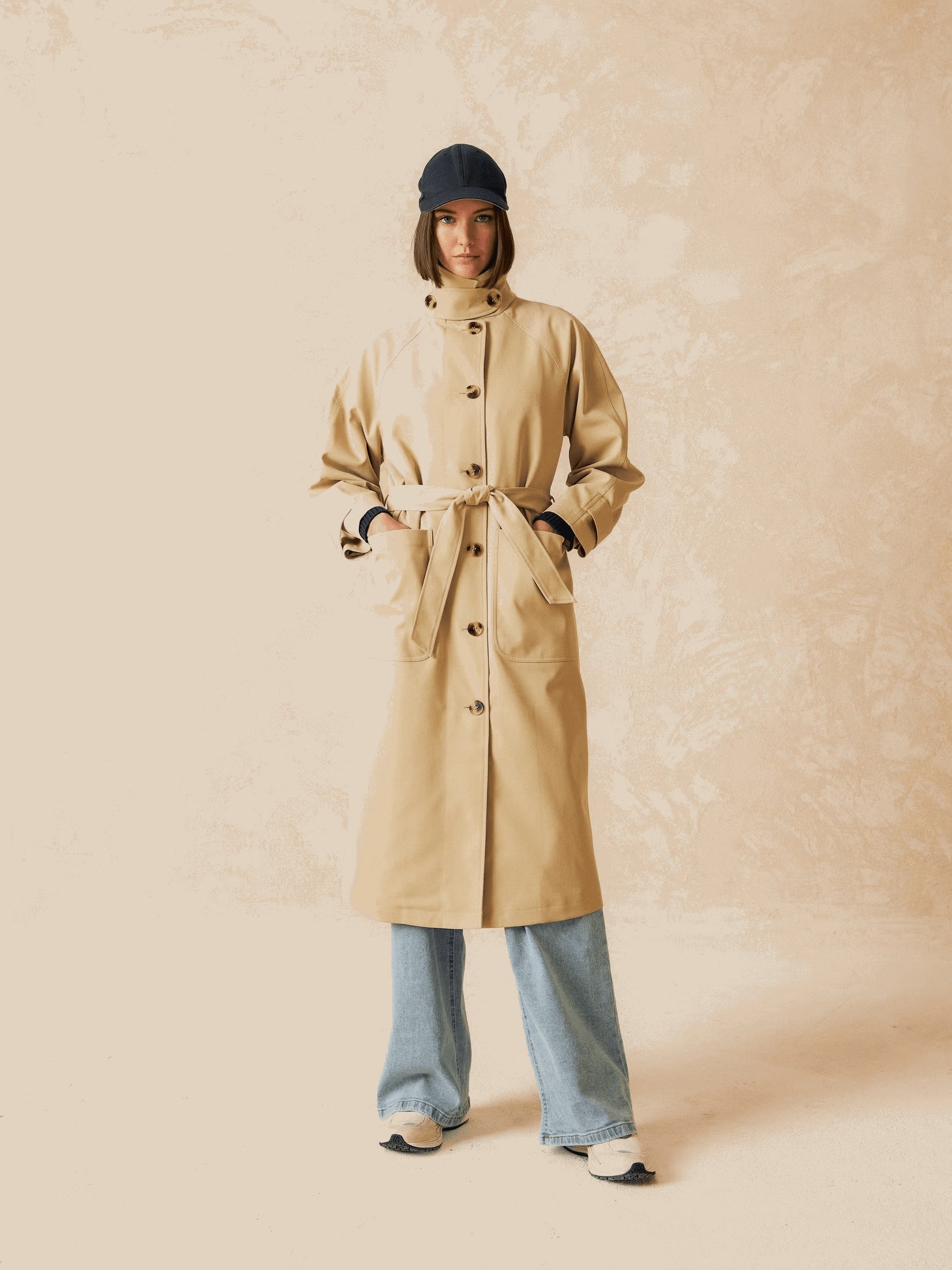 A model wearing a long beige trench coat.