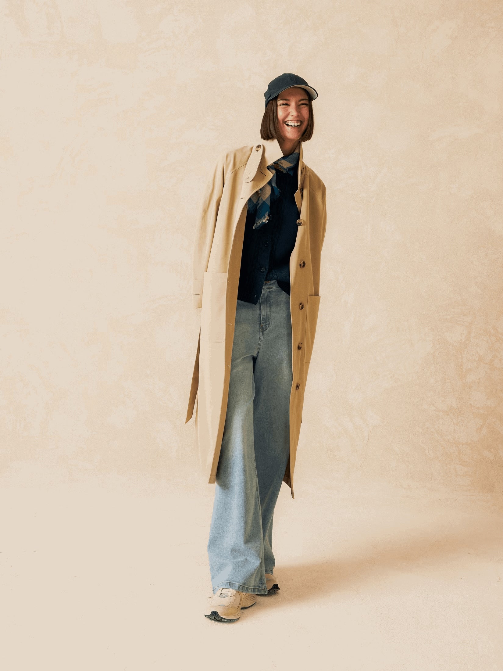 A model wearing a long beige trench coat.