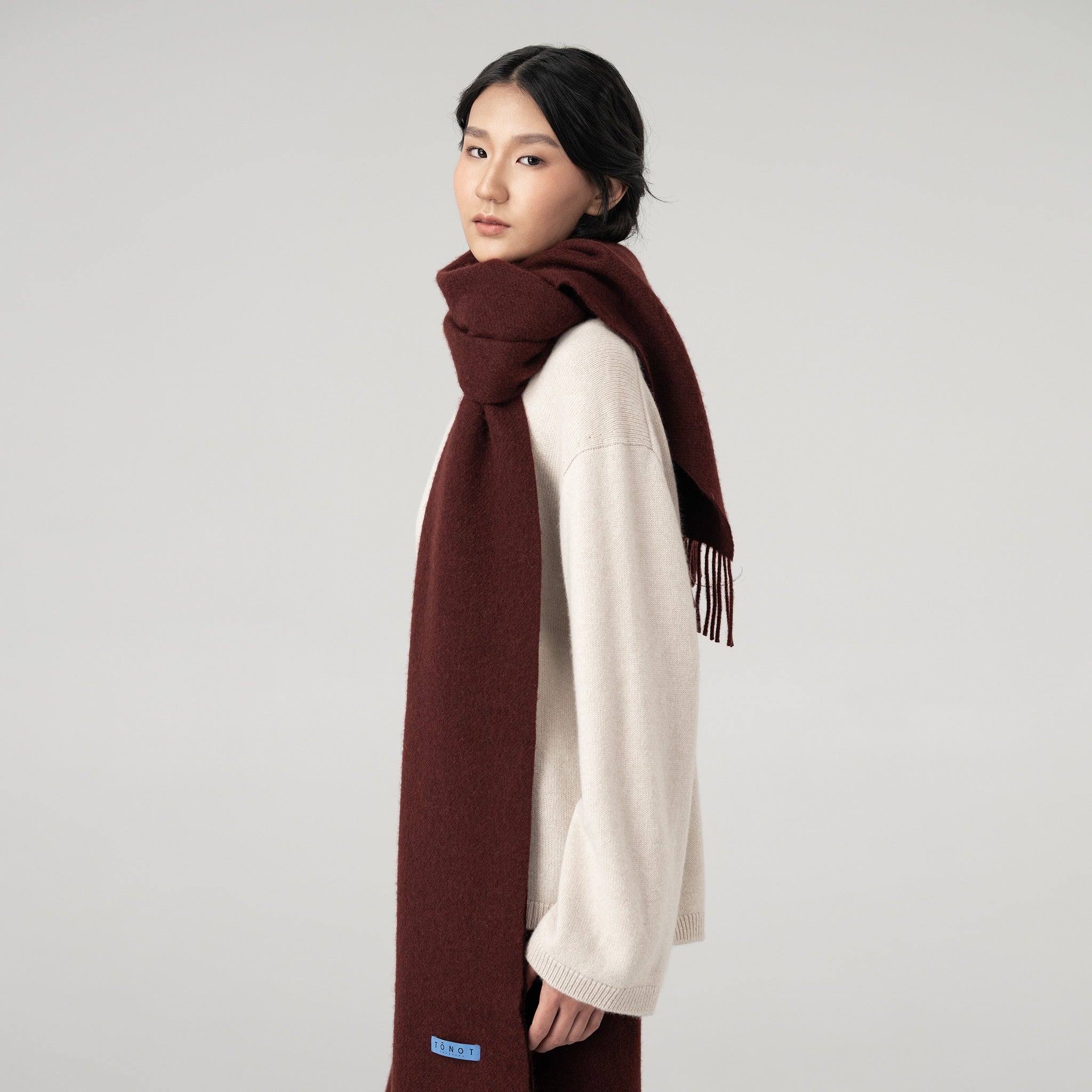 Model wearing a long cashmere scarf in mocha color.