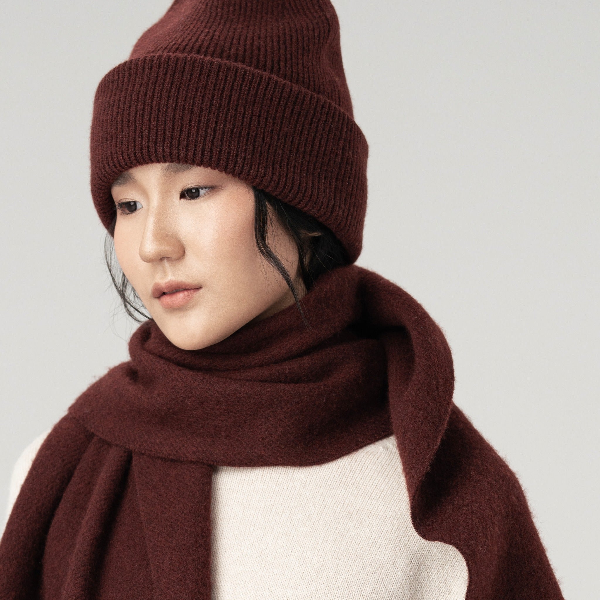 Model wearing a mocha-colored cashmere scarf and matching beanie set.