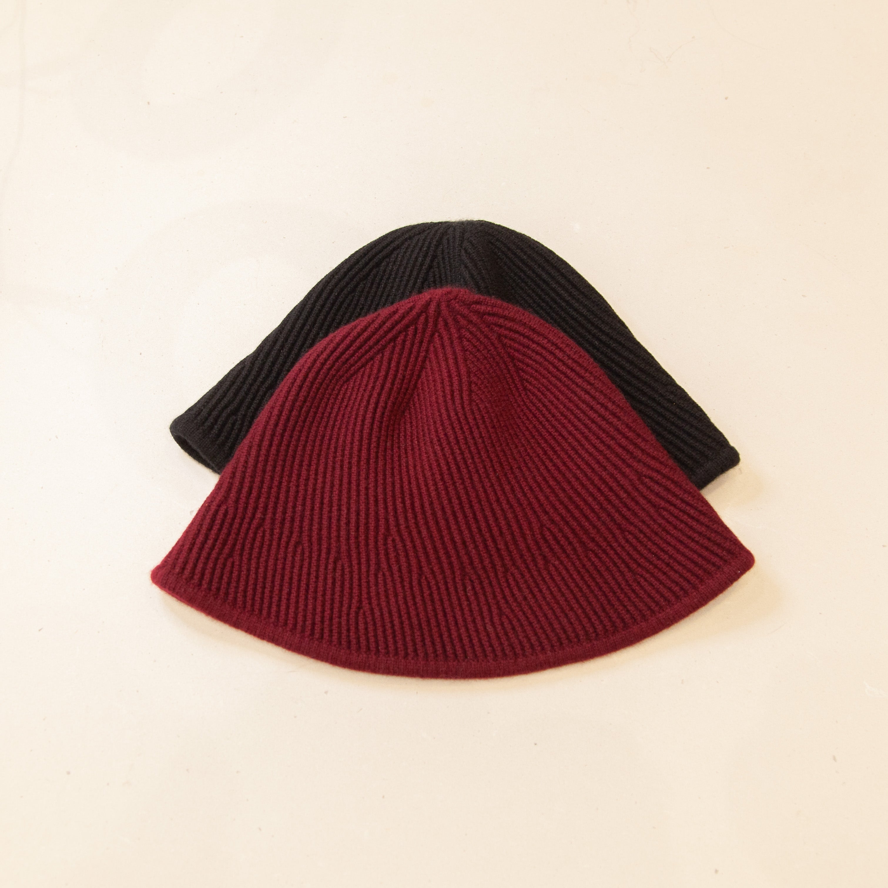 Flat lay of red and black cashmere bucket hat, featuring a soft texture and stylish, versatile design.