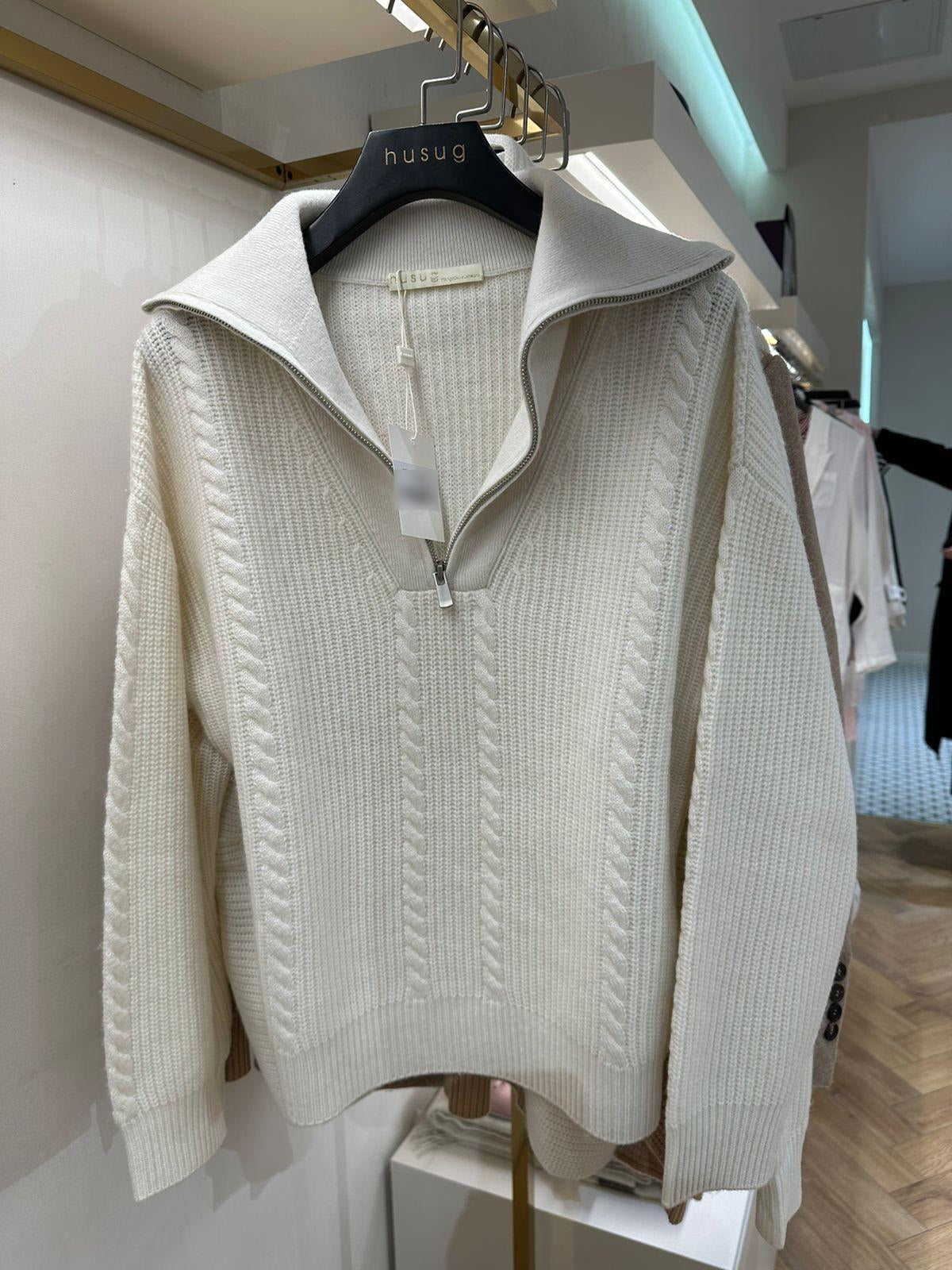 White 100% cashmere sweater with wide ribbing, cable-knit details, and a quarter-zip closure, offering a blend of sophistication and comfort.