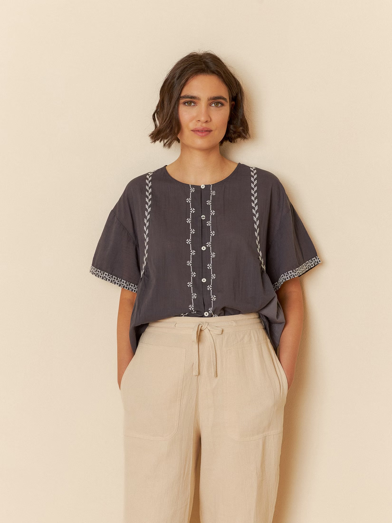 Model wearing a carbon cotton embroidery trapeze shirt, featuring intricate stitching details.