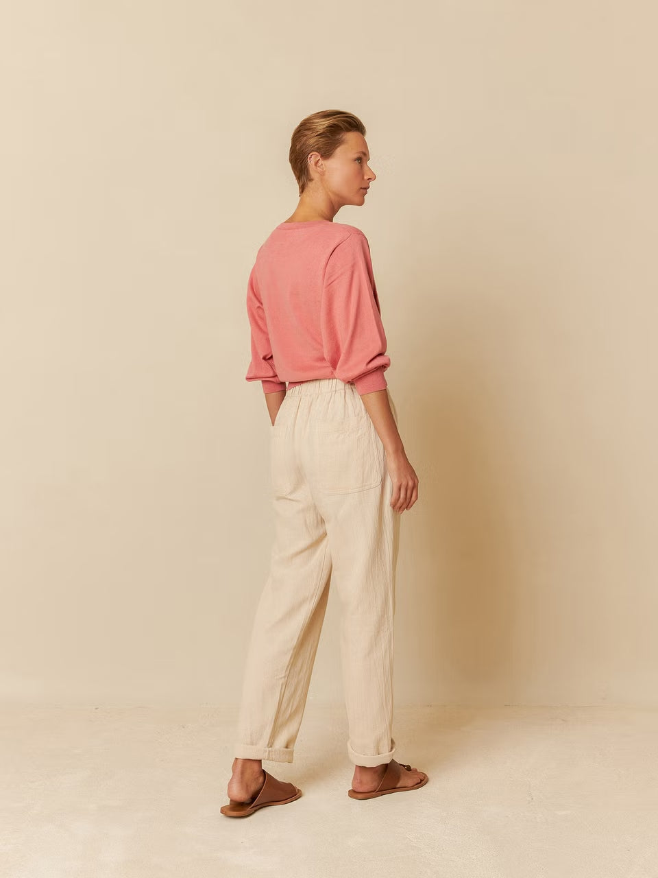 A model wearing organic cotton pants and a pink shirt.