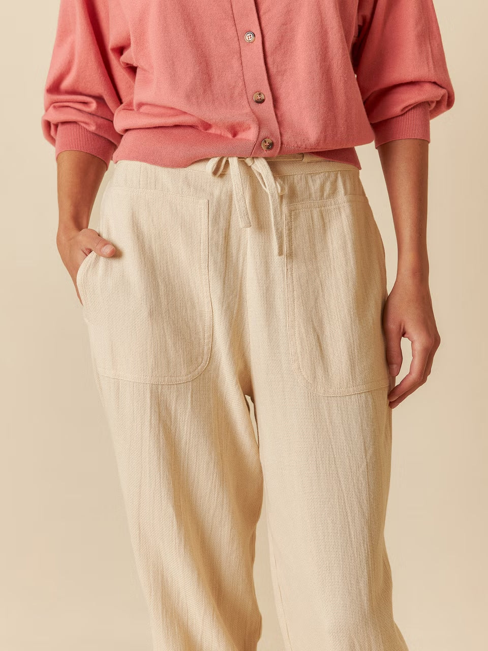 A model wearing organic cotton pants and a pink shirt.