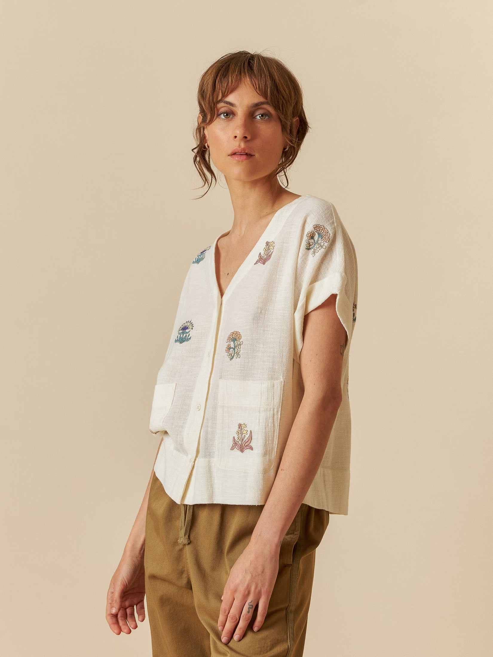 Model wearing an ecru embroidered organic cotton shirt with delicate stitching details