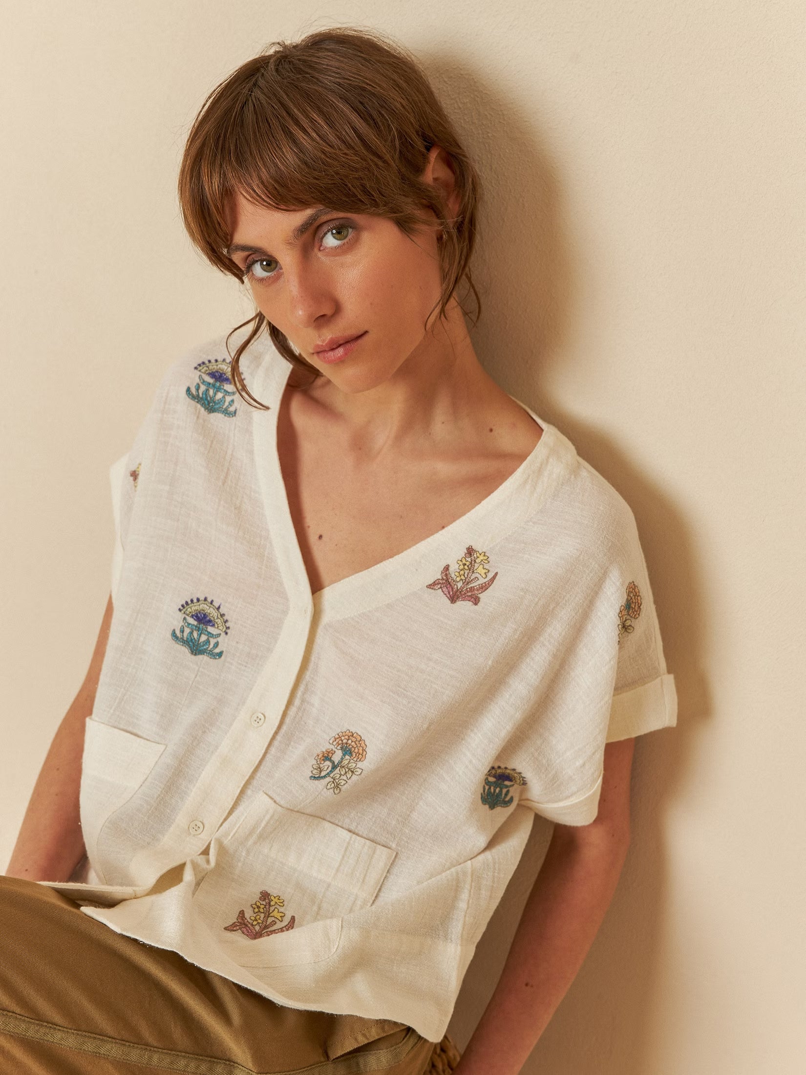 Model wearing an ecru embroidered organic cotton shirt with delicate stitching details