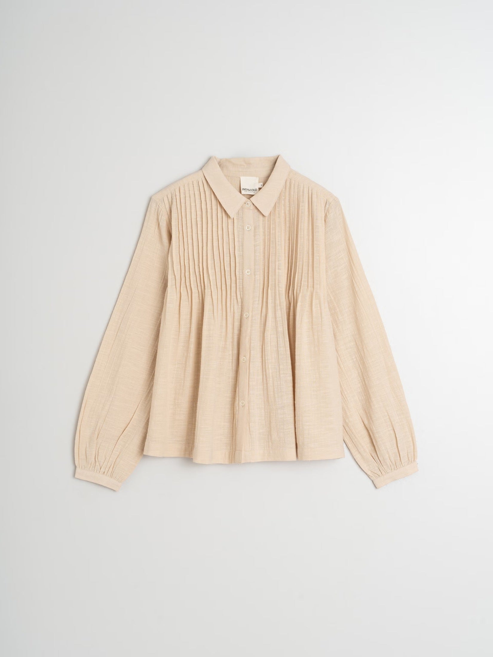 Flat lay of a beige organic cotton blouse with pintuck details.