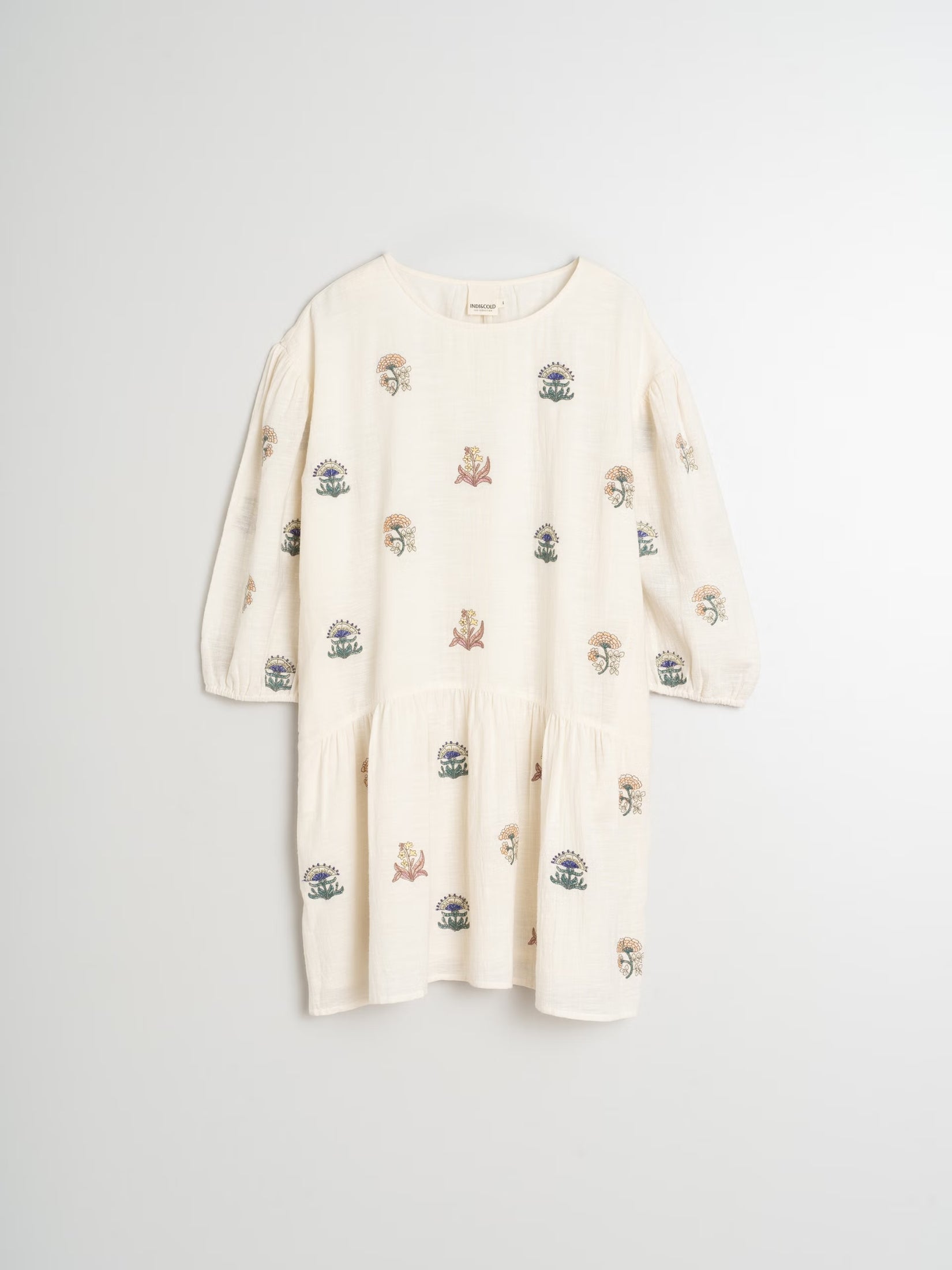 Flat lay of an organic cotton embroidered dress, showcasing its delicate embroidery and natural fabric.