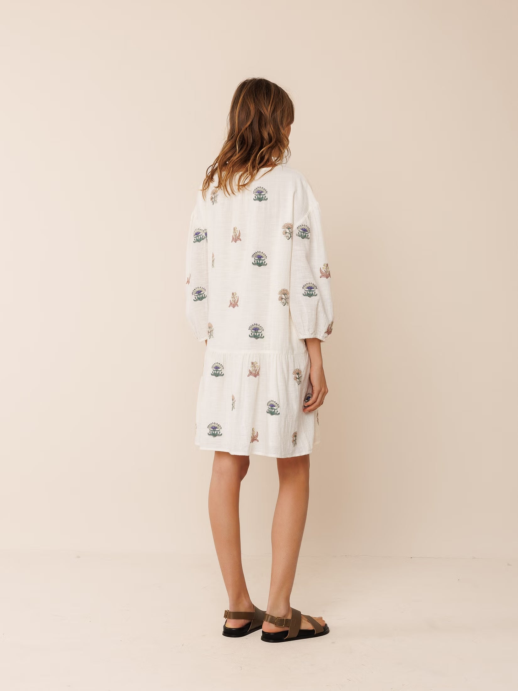 Model wearing an organic cotton embroidered dress, featuring intricate stitching details