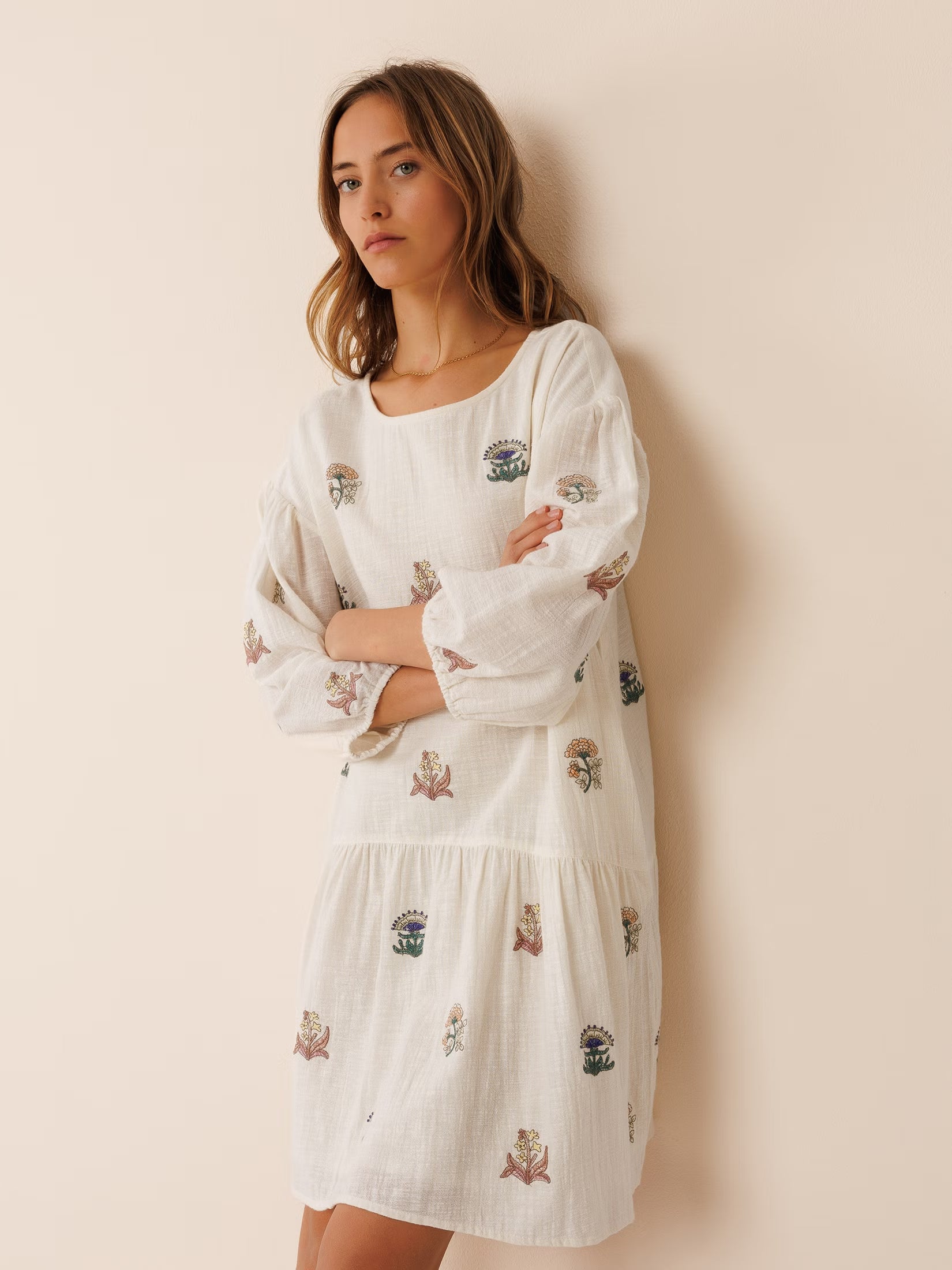 Model wearing an organic cotton embroidered dress, featuring intricate stitching details