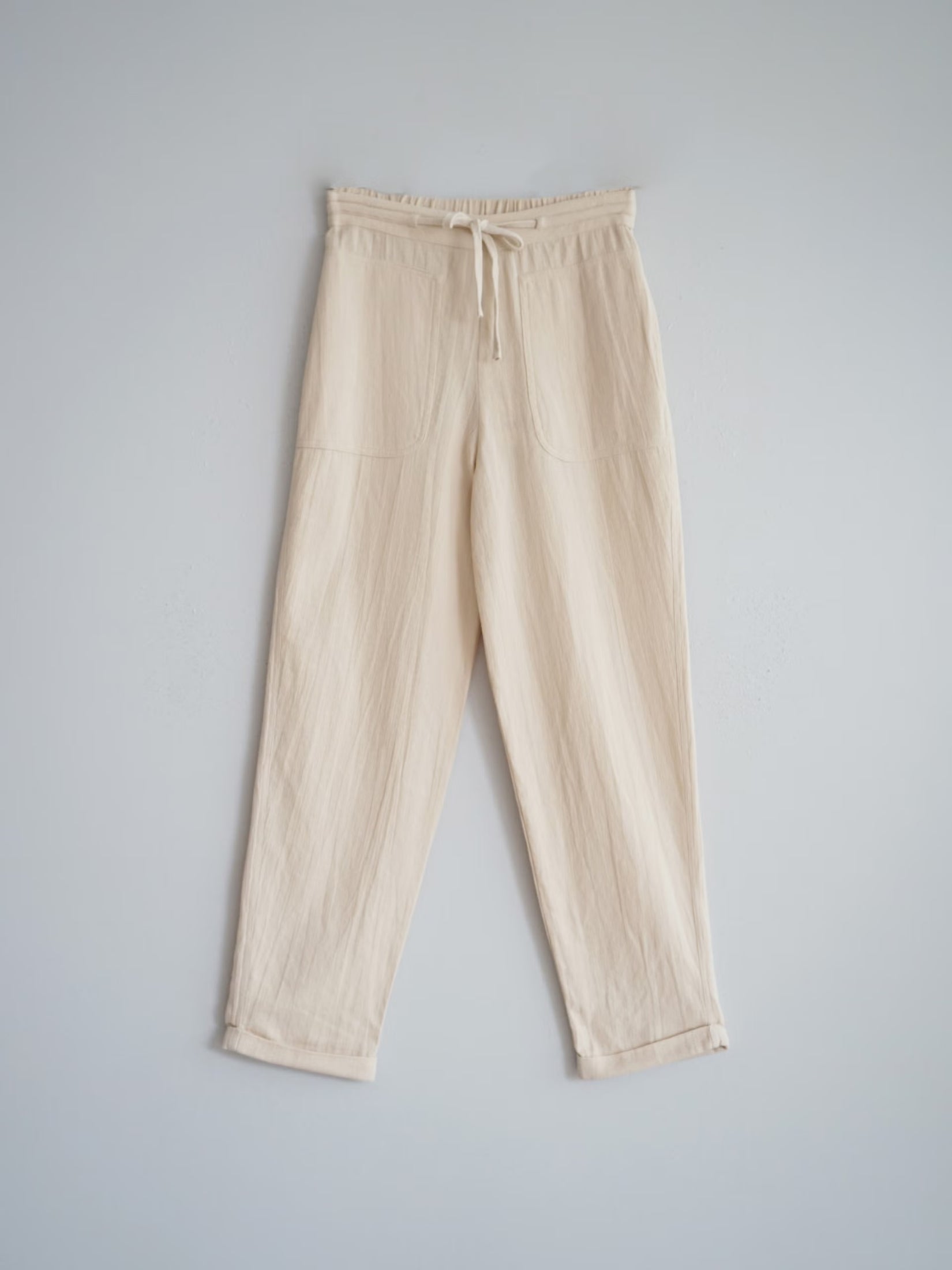 Ecru cotton pants with waist ties, relaxed fit.